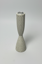 A modern ceramic candle holder with a fluted upper section and a ribbed conical base, in a speckled light gray glaze with a silver metal rim at the top, set against a neutral light gray background.